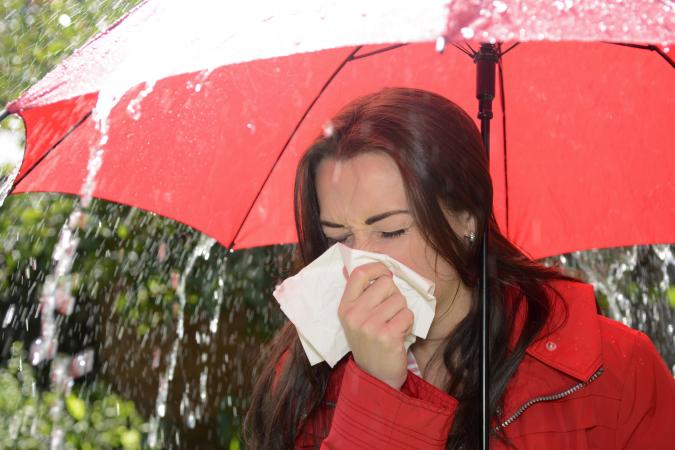 Woman sneezing in rain