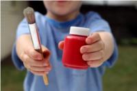 little boy holding red paint and paint brush