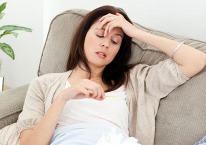 Woman feeling ill and looking at thermometer