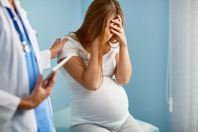 Doctor comforting worried young pregnant woman