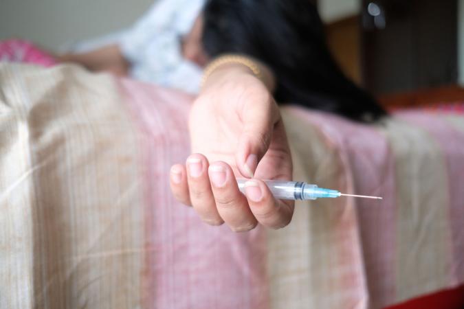 woman holding syringe on bed
