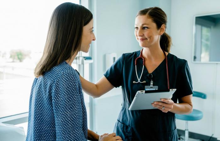 Female doctor consoling woman while holding tablet