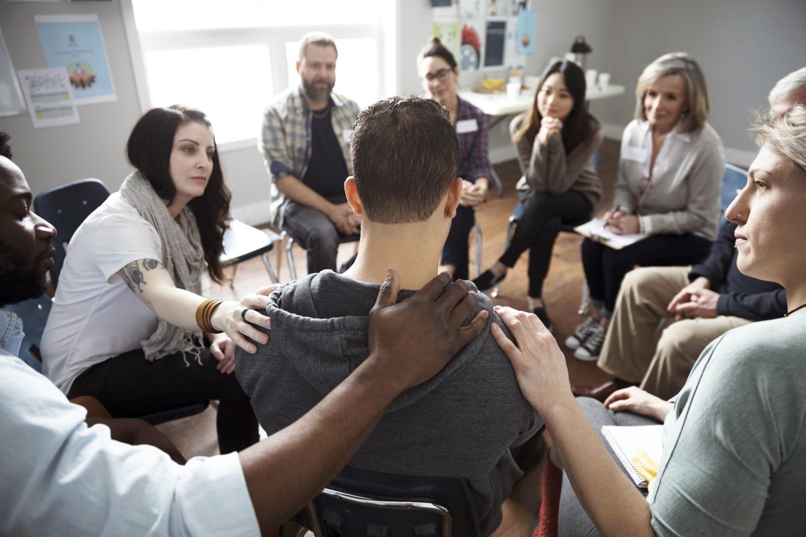 People comforting man in support at support group in community center
