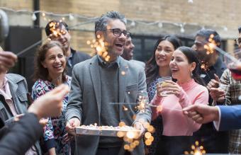 Amigos celebrando el cumpleaños con pastel y bengalas