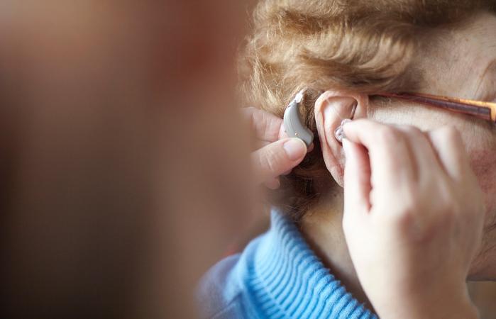Mujer colocandose auriculares para la sordera