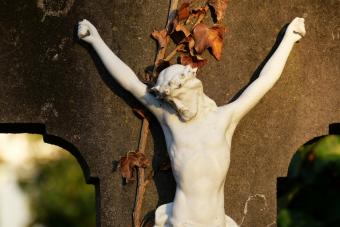 Abandoned white crucifix on a gray stone under sunlight