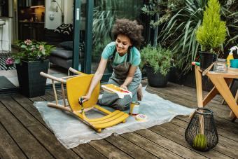 Woman is coloring a chair at home 