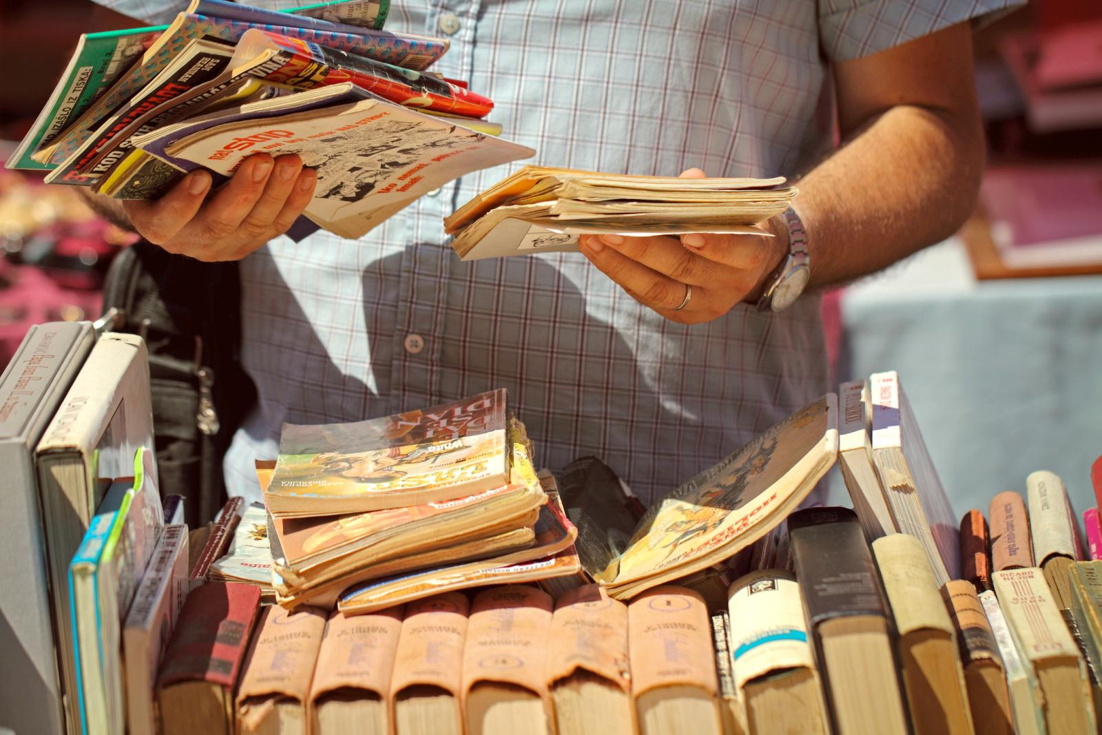 Man Holding Books At Flea Market