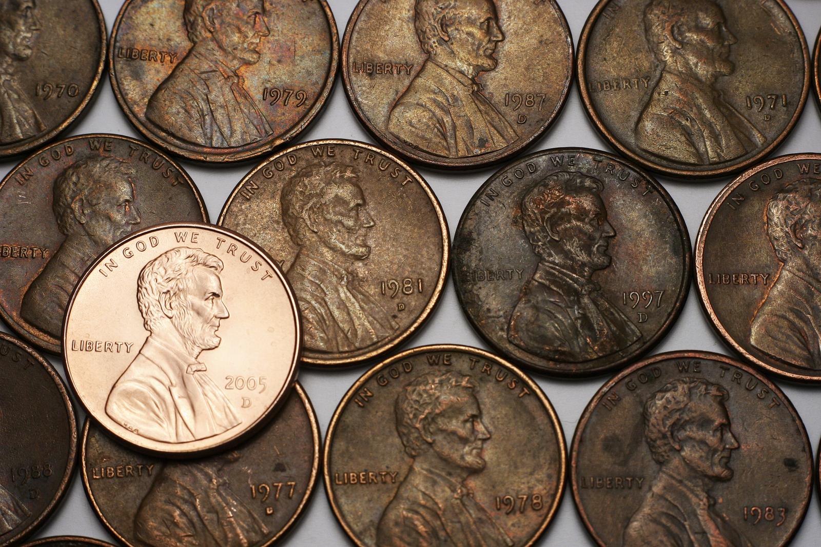Three lines of old pennies and one shiny new one