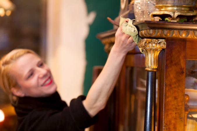 Smiling Woman Cleaning Antique Wooden Cabinet