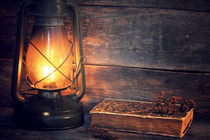 Illuminated Antique Lantern With Old Book On Table