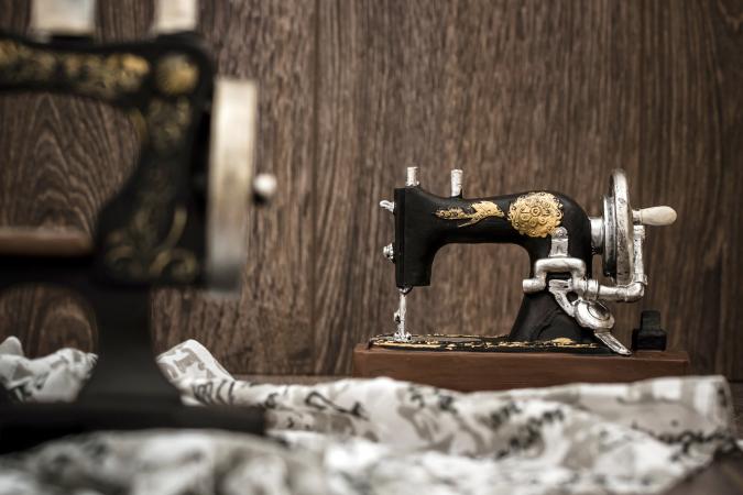 Small nostalgic decorative sewing machine on brown wooden background