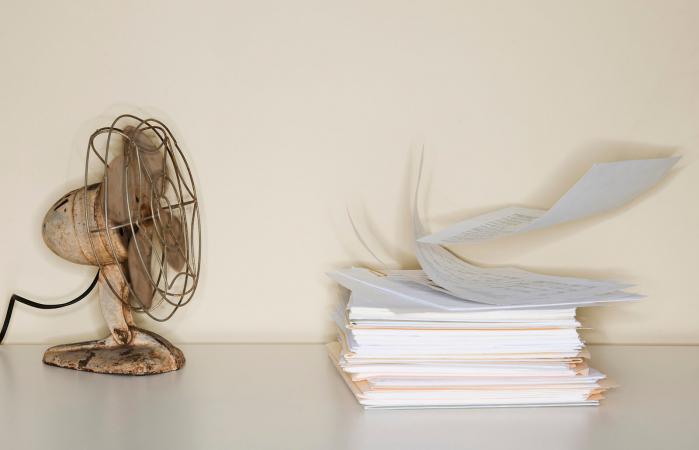 Electric fan blowing on heap of papers