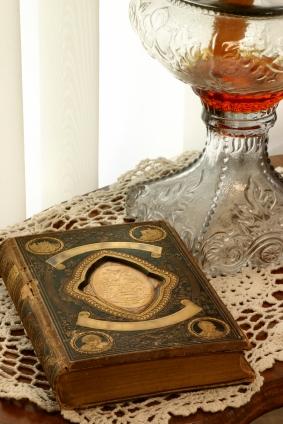 Antique book, lamp and doilies on table