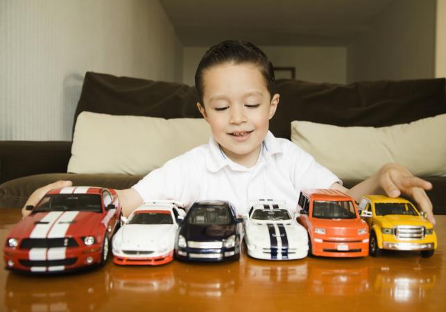boy lining up toy cars