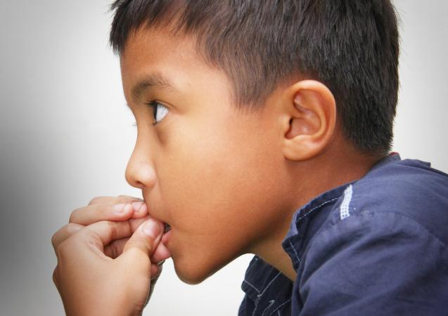 Young boy chewing on fingers