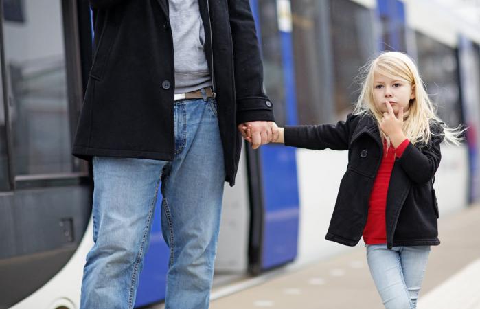 girl traveling on public transport with her father