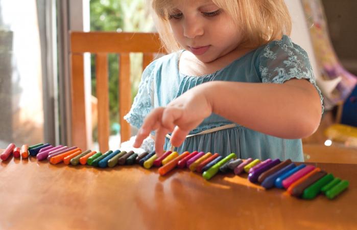 Girl lining up crayons in a row