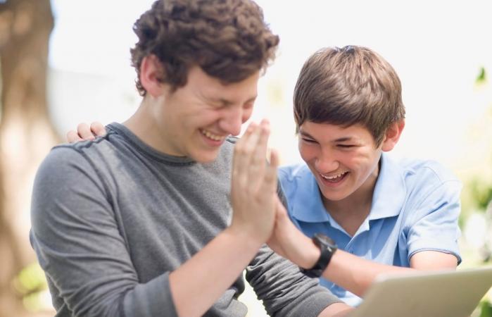 Teenage boys using laptop together