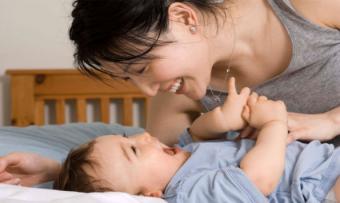 Mother playing with baby on bed