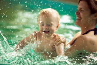 Mother splashing with baby son in swimming pool