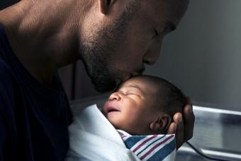 Father kissing forehead of newborn son