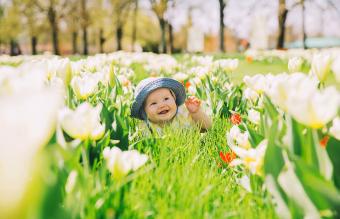 baby in green grass of tulips field