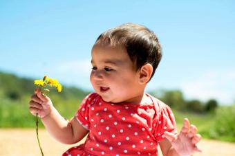 Smiling Girl Holding Yellow Flowers Against Sky