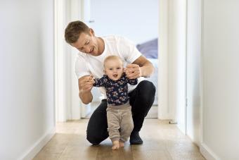 Man teaching little son to walk in corridor