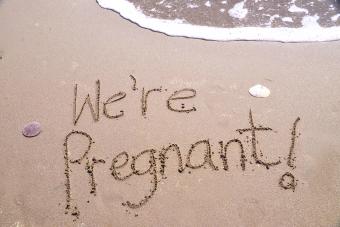 We're Pregnant! Written in beach sand 