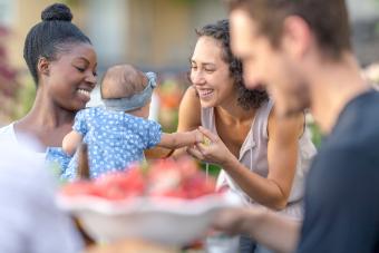 Mom holds baby daughter in her lap at an outdoor dining table