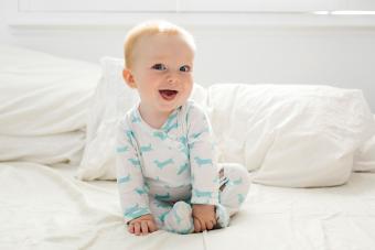 Baby boy (6-11 months) lying on bed 