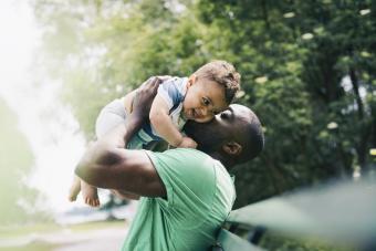 Father kissing happy son while carrying at park