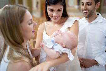 Mother giving son to godparents at baptism celebration