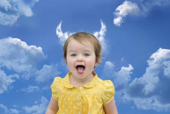 Baby girl in a yellow dress under cloud horns