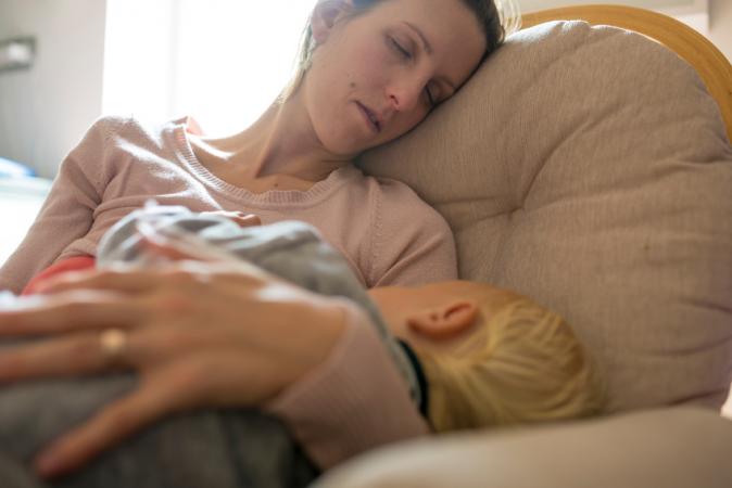 Mother sleeping in rocking chair with baby