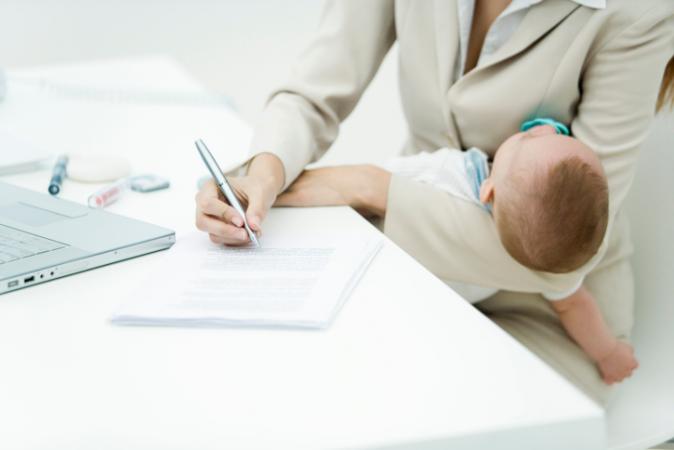 Woman signing document holding baby