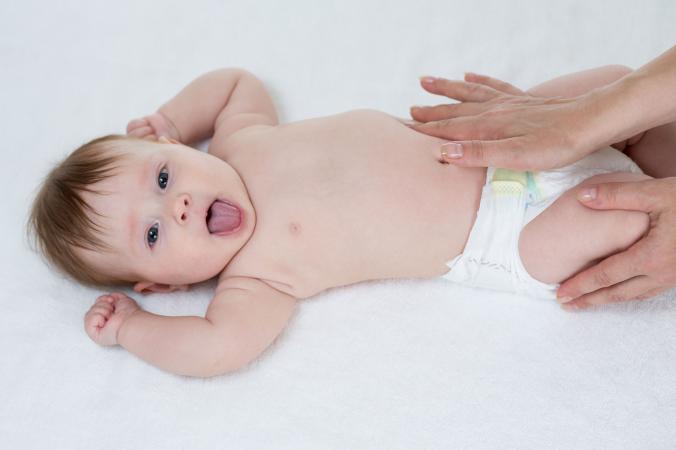 Mother giving baby stomach massage