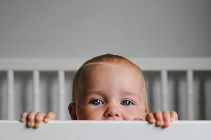 Baby peeking over crib rail