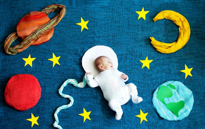 Baby on the floor with cushions that look like planets