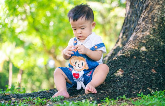 baby boy sitting by tree
