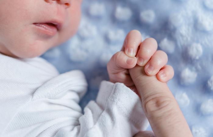 Newborn baby boy holding finger