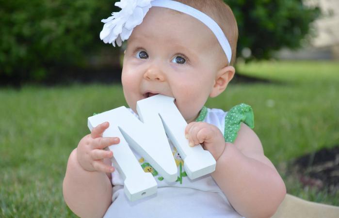 Cute baby girl with wooden M