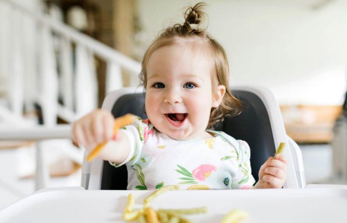 Baby girl eating in high chair