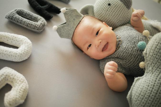 Baby Boy With Stuffed Letters Lying On Bed