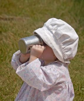 Baby girl drinking from a tin mug