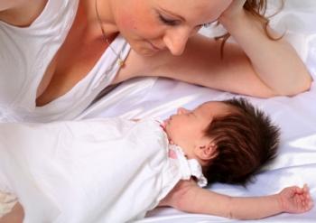 Mom watching infant wearing a sleeping bag