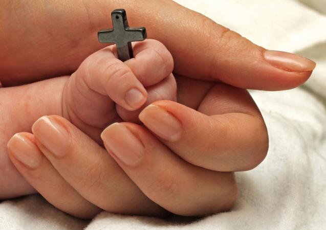 Bebé sosteniendo una cruz