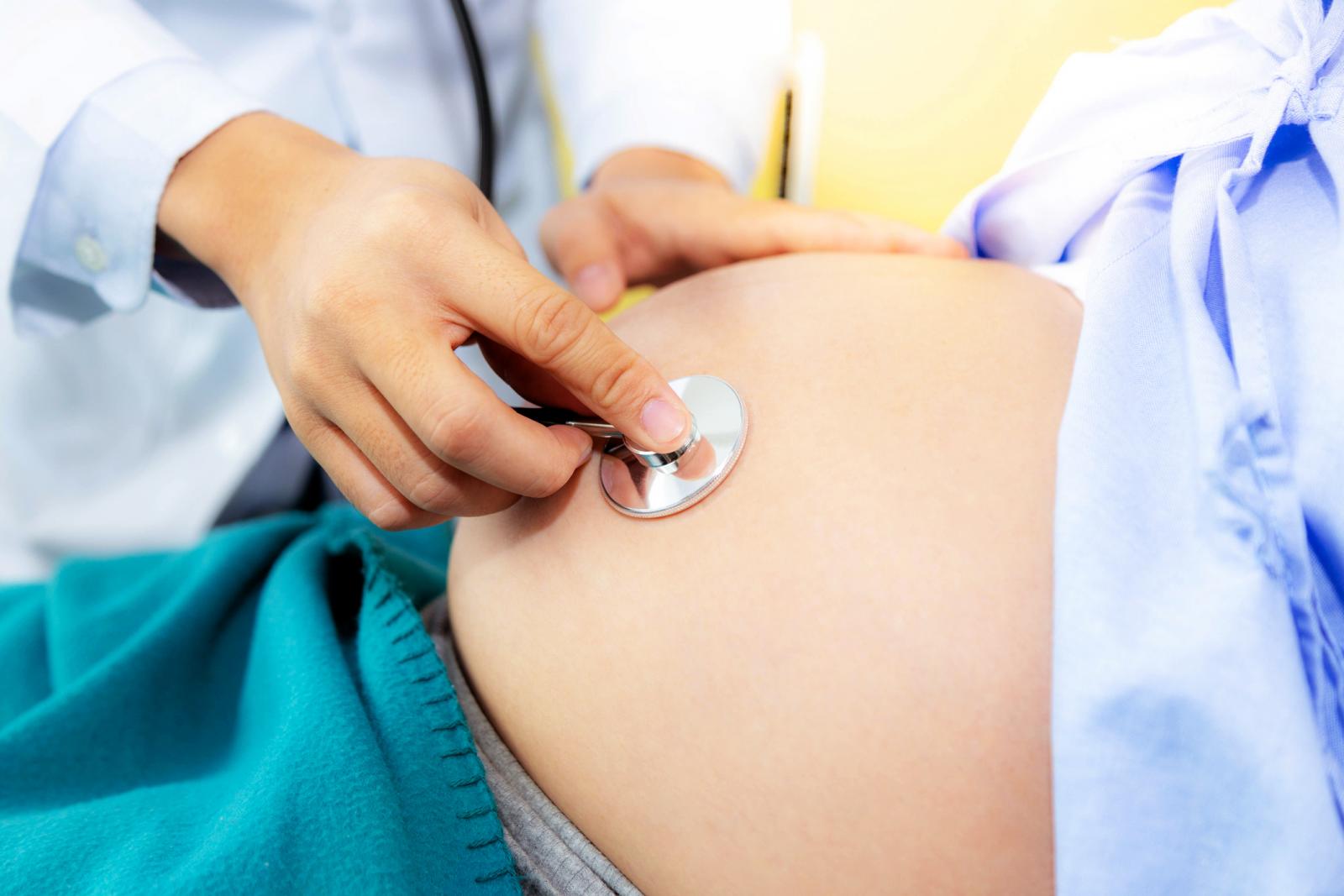 Doctor is checking fetus heartbeat and fetus position at mother belly by using stethoscope