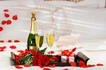 champagne, chocolates, rose petals on bed